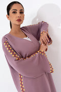 Dubai lady wearing a mauve purple dress with floral embellishments on a white background